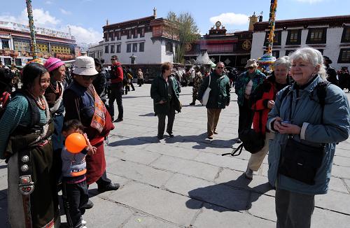     3月31日，几名外国游客在拉萨大昭寺广场游览。 随着天气变暖，西藏旅游逐渐升温，国内外游客开始进入西藏。据了解，2009年，西藏接待国内外游客达561.06万人次，旅游总收入55.99亿元；2010年西藏计划接待国内外游客600万人次以上。 新华社记者 觉果 摄