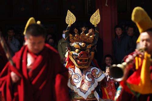 2月27日，塔尔寺一名僧人头戴面具在法号的伴奏下跳神。 当日，位于青海省西宁市湟中县境内的藏传佛教名寺塔尔寺举行隆重的“跳欠”仪式。“跳欠”俗称“跳神舞”，是一种重要的宗教仪式。表演者为寺院的僧人，他们头戴面具，身着色彩艳丽的服饰，用手势和动作表达各种佛教寓意，并由专门的僧人用舞钹、唢呐等伴奏。塔尔寺跳神活动距今已有近300年的历史。 新华社记者 张宏祥 摄