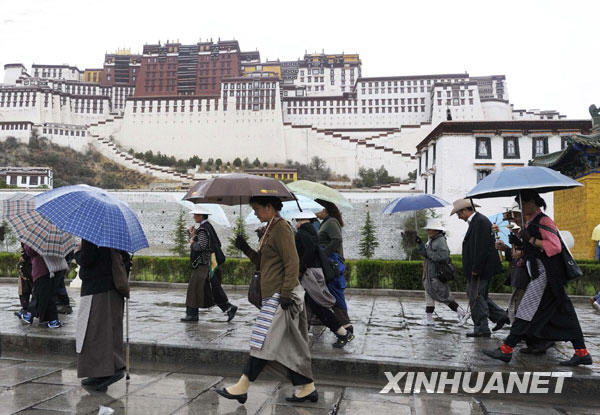 6月28日，拉萨市民雨中从布达拉宫广场前走过。 新华社记者 普布扎西 摄