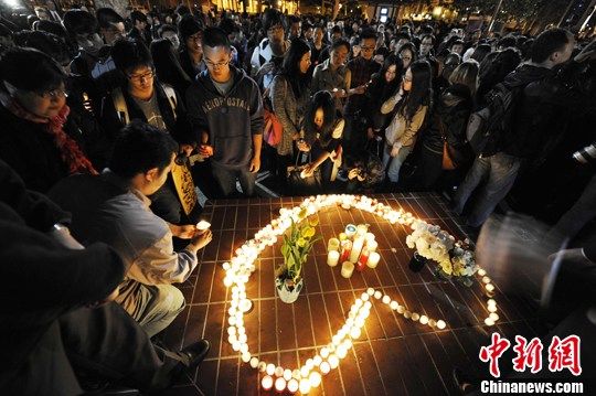 当地时间4月11日晚，南加州大学上千名同学在洛杉矶雨后的瑟瑟寒风中手捧蜡烛与鲜花，含泪悼念于当日凌晨不幸中枪遇害的两名同学。中新社发 毛建军 摄  