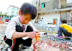 盈江震后生活逐渐恢复正常，一个小朋友在震后的街道上帮妈妈削胡萝卜。 